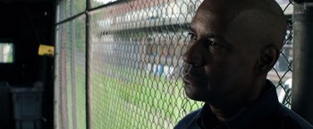 Movie still from “The Equalizer” (2014), directed by Antoine Fuqua – A person near a chain link fence; Close Up shot, Over the shoulder angle