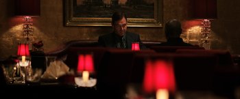 Movie still from “The Equalizer” (2014), directed by Antoine Fuqua – A man sitting at a table in front of a painting; Medium shot, Over the shoulder angle