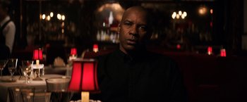 Movie still from “The Equalizer” (2014), directed by Antoine Fuqua – A man sitting in front of a red table lamp; Close Up shot, Over the shoulder angle
