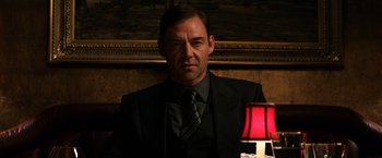 Movie still from “The Equalizer” (2014), directed by Antoine Fuqua – A man in a suit and tie in front of a lamp; Medium shot, Low angle