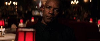 Movie still from “The Equalizer” (2014), directed by Antoine Fuqua – A man in a black shirt is in a dark room; Close Up shot, Over the shoulder angle