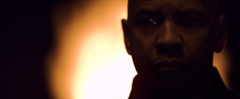 Movie still from “The Equalizer” (2014), directed by Antoine Fuqua – A man is looking at the camera in front of a fire; Close Up shot, Low angle