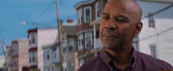 Movie still from “The Equalizer” (2014), directed by Antoine Fuqua – A person wearing a purple shirt near some buildings; Close Up shot, Low angle