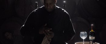 Movie still from “The Equalizer 3” (2023), directed by Antoine Fuqua – A man in a black shirt is holding something in his hands; Medium shot, Low angle