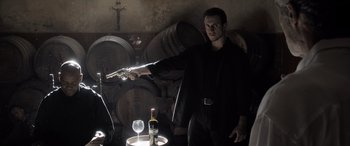 Movie still from “The Equalizer 3” (2023), directed by Antoine Fuqua – A man holding a gun pointed at a wine glass; Medium shot, Low angle