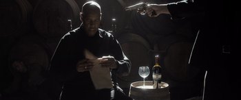 Movie still from “The Equalizer 3” (2023), directed by Antoine Fuqua – A man sitting in front of a wine glass; Medium shot, Low angle