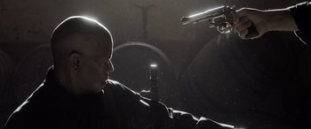 Movie still from “The Equalizer 3” (2023), directed by Antoine Fuqua – A bald man with a gun pointed at him in a dark room; Close Up shot, Low angle