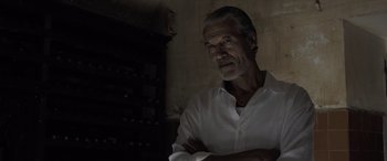 Movie still from “The Equalizer 3” (2023), directed by Antoine Fuqua – An older man in a white dress shirt is standing in a dark room; Close Up shot, Low angle