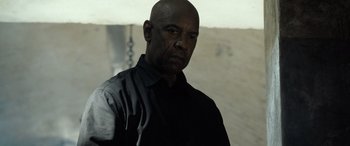 Movie still from “The Equalizer 3” (2023), directed by Antoine Fuqua – A man in a black shirt is looking at the camera; Close Up shot, Low angle