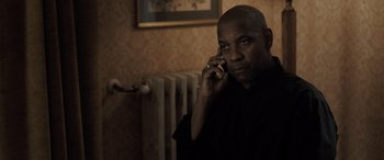 Movie still from “The Equalizer 3” (2023), directed by Antoine Fuqua – A man talking on a cell phone while sitting in front of a radiator; Close Up shot, Over the shoulder angle