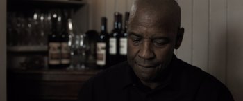 Movie still from “The Equalizer 3” (2023), directed by Antoine Fuqua – A man in a black shirt is looking down at his face; Close Up shot, Low angle
