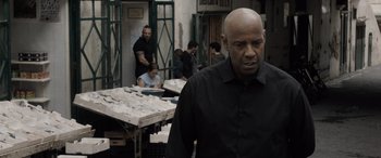 Movie still from “The Equalizer 3” (2023), directed by Antoine Fuqua – A man standing in front of a table with papers on top of it; Medium shot, Over the shoulder angle