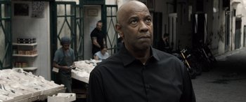 Movie still from “The Equalizer 3” (2023), directed by Antoine Fuqua – A man in a black shirt is looking at the camera; Close Up shot, Over the shoulder angle