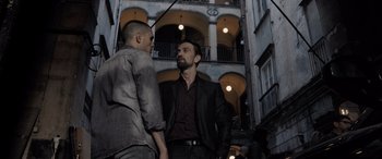 Movie still from “The Equalizer 3” (2023), directed by Antoine Fuqua – Two men standing next to each other in front of a building; Medium shot, Over the shoulder angle