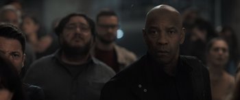 Movie still from “The Equalizer 3” (2023), directed by Antoine Fuqua – A man in a black shirt is standing next to two other men; Close Up shot, Low angle