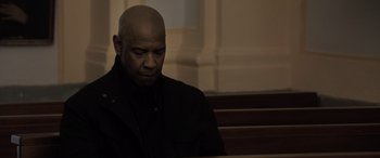 Movie still from “The Equalizer 3” (2023), directed by Antoine Fuqua – A man sitting at a table in front of a window; Medium shot, Low angle