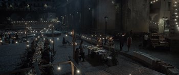 Movie still from “The Equalizer 3” (2023), directed by Antoine Fuqua – A group of people sitting at tables in a courtyard at night; Extreme Wide shot, High angle