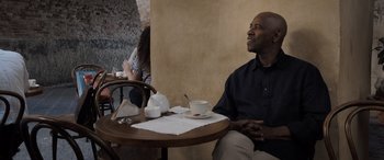 Movie still from “The Equalizer 3” (2023), directed by Antoine Fuqua – A man sitting at a table with a cup of coffee; Medium shot, Over the shoulder angle