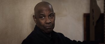 Movie still from “The Equalizer 3” (2023), directed by Antoine Fuqua – A man with a bald head is sitting against a wall; Close Up shot, Low angle