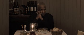 Movie still from “The Equalizer 3” (2023), directed by Antoine Fuqua – A man sitting at a dinner table with a cigarette in his mouth; Medium shot, Over the shoulder angle