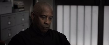 Movie still from “The Equalizer 3” (2023), directed by Antoine Fuqua – A man in a black shirt is looking down at his face; Close Up shot, Low angle