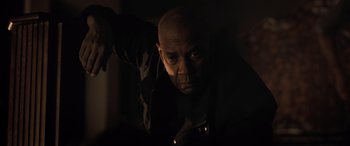 Movie still from “The Equalizer 3” (2023), directed by Antoine Fuqua – A bald man is looking at the camera in the dark; Close Up shot, Low angle