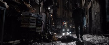 Movie still from “The Equalizer 3” (2023), directed by Antoine Fuqua – A street scene with a person laying on the ground; Wide shot, Over the shoulder angle