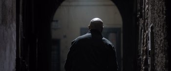 Movie still from “The Equalizer 3” (2023), directed by Antoine Fuqua – A bald man in a black jacket looking into an arched doorway; Medium shot, Over the shoulder angle