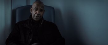 Movie still from “The Equalizer 3” (2023), directed by Antoine Fuqua – A man sitting in a chair in front of a blue wall; Close Up shot, Low angle