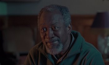 An older man with a gray beard is smiling for the camera