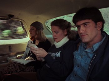 Movie still from “The Evil Dead” (1981), directed by Sam Raimi – A group of people sitting in the back of a car; Medium shot, High angle
