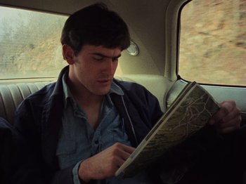 Movie still from “The Evil Dead” (1981), directed by Sam Raimi – A man sitting in the back of a car looking at a map; Close Up shot, High angle