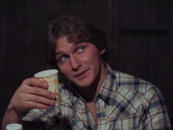 Movie still from “The Evil Dead” (1981), directed by Sam Raimi – A young man holding a coffee cup up to his face; Close Up shot, Over the shoulder angle