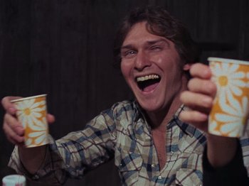 Movie still from “The Evil Dead” (1981), directed by Sam Raimi – A man is holding two cups and laughing; Close Up shot, Low angle