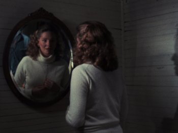 Movie still from “The Evil Dead” (1981), directed by Sam Raimi – A woman looking in the mirror in front of a mirror; Medium shot, Over the shoulder angle