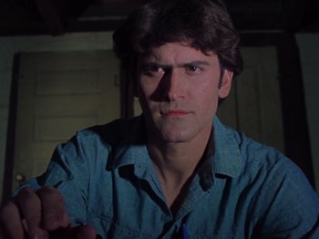 Movie still from “The Evil Dead” (1981), directed by Sam Raimi – A man with a beard is looking at the camera; Close Up shot, Low angle