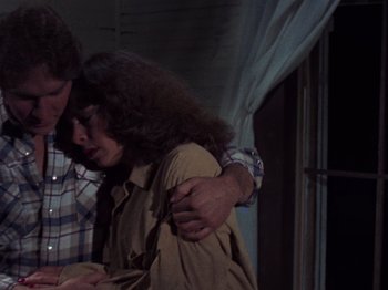 Movie still from “The Evil Dead” (1981), directed by Sam Raimi – A man and a woman hugging each other in front of a window; Medium shot, Low angle