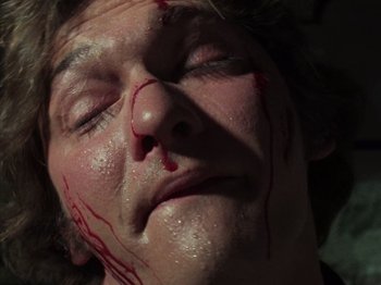 Movie still from “The Evil Dead” (1981), directed by Sam Raimi – A man with blood all over his face and neck; Extreme Close Up shot, High angle