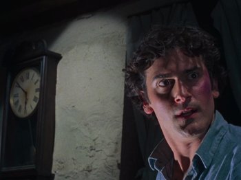 Movie still from “The Evil Dead” (1981), directed by Sam Raimi – A man with a surprised look on his face in front of a clock; Close Up shot, Low angle