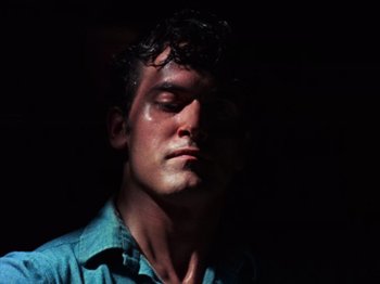 Movie still from “The Evil Dead” (1981), directed by Sam Raimi – A man with his eyes closed in the dark; Close Up shot, Low angle
