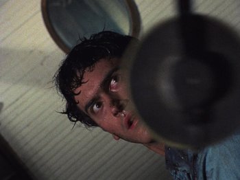 Movie still from “The Evil Dead” (1981), directed by Sam Raimi – A person looking at a mirror; Close Up shot, Low angle