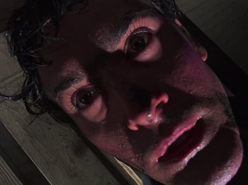 Movie still from “The Evil Dead” (1981), directed by Sam Raimi – A man's face in the dark; Extreme Close Up shot, Overhead angle