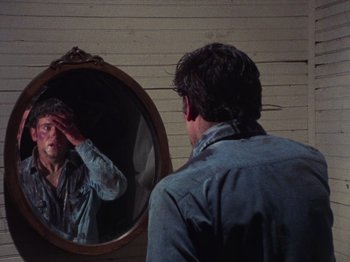 Movie still from “The Evil Dead” (1981), directed by Sam Raimi – A man looking in the mirror while touching his forehead; Close Up shot, Over the shoulder angle