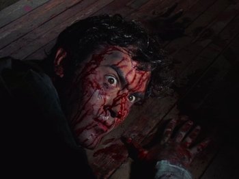 Movie still from “The Evil Dead” (1981), directed by Sam Raimi – A man with blood all over his face and body; Close Up shot, Overhead angle
