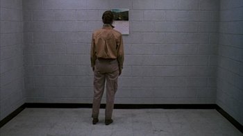 Movie still from “Day of the Dead” (1985), directed by George A. Romero – A man standing in front of a brick wall looking at a calendar; Wide shot, Low angle