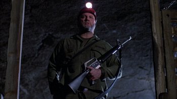 Movie still from “Day of the Dead” (1985), directed by George A. Romero – A man holding a rifle with a light on it; Medium shot, Low angle