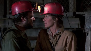 Movie still from “Day of the Dead” (1985), directed by George A. Romero – A man and a woman wearing hard hats and talking to each other; Close Up shot, Over the shoulder angle