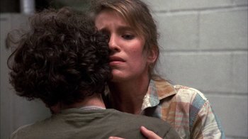 Movie still from “Day of the Dead” (1985), directed by George A. Romero – A woman hugging a man in front of a brick wall; Close Up shot, Over the shoulder angle
