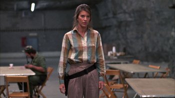 Movie still from “Day of the Dead” (1985), directed by George A. Romero – A woman in a plaid shirt holding a gun; Medium shot, Low angle