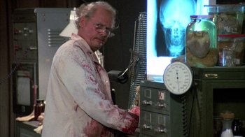 Movie still from “Day of the Dead” (1985), directed by George A. Romero – An old man in a white lab coat is holding a tool; Medium shot, Low angle